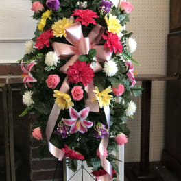 Standing floral spray with pink ribbon and mixed bright flowers