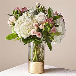 White and blush roses with hydrangeas in a clear glass vase