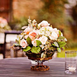 Low floral centerpiece with pale pink roses in a decorative bowl on a table