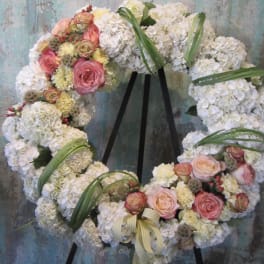 Floral wreath of white hydrangeas and pink roses on a black stand