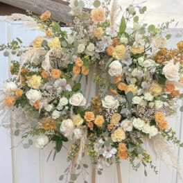 Large floral wreath with white and peach roses on an easel
