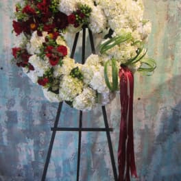Heart-shaped floral wreath with red and white flowers on an easel