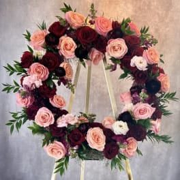 Heart-shaped wreath of pink and burgundy roses on a stand