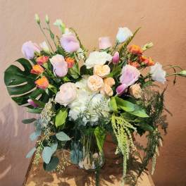 Pastel bouquet of roses and white blooms in a clear glass vase