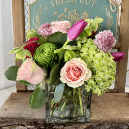 Pink roses and green hydrangeas in a clear square vase