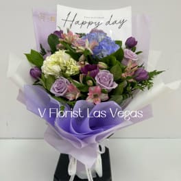 Bouquet of lavender and blue flowers wrapped in purple paper