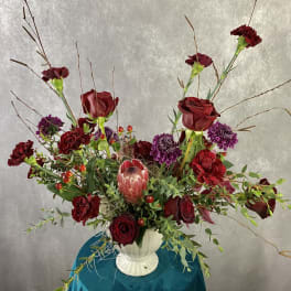 Red roses and purple flowers in a white vase