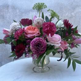 Pink and burgundy mixed flower arrangement in a silver vase
