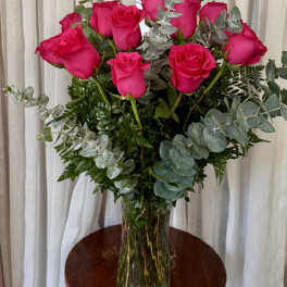 Hot pink roses in a clear glass vase with eucalyptus