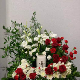 Red and white floral arrangement with a white urn and cross centerpiece