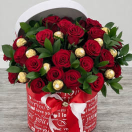 Red roses and gold-wrapped chocolates in a heart-themed gift box
