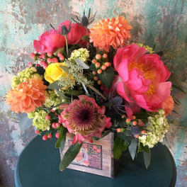 Colorful bouquet with pink and orange blooms in a wooden box
