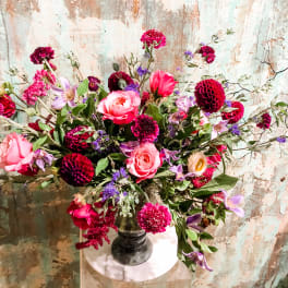 Large mixed bouquet of pink and purple flowers in a dark vase