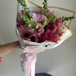Pink mixed flower bouquet wrapped in white paper with a pink ribbon