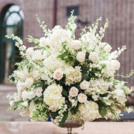Large white floral arrangement in a silver pedestal bowl