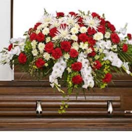 Red and white funeral spray on a wooden casket