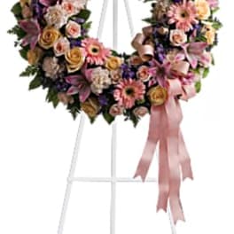 Large floral wreath on a white easel with a pink ribbon
