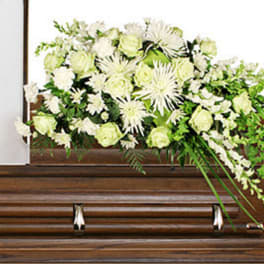 White floral casket spray on a wooden casket