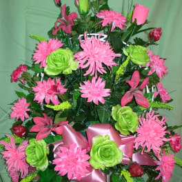 Pink and green floral arrangement in a white pot with a pink ribbon