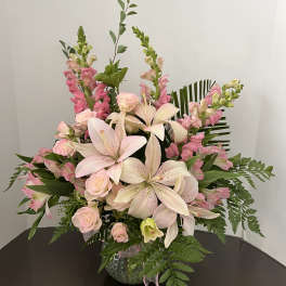 Pink lilies and roses arranged in a glass vase