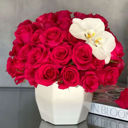Hot pink roses in a white vase with white orchids