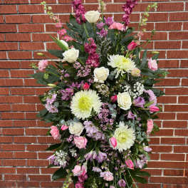Tall standing spray of white, pink, and lavender flowers displayed on an easel.