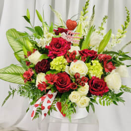Red and white rose arrangement in a white vase with a Valentine topper