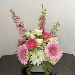 Pink gerberas and white roses in a low square vase