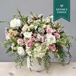 Large pastel floral arrangement in a white textured vase