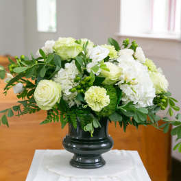 White and pale green floral arrangement in a dark vase