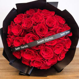 Bouquet of red roses wrapped in black paper with a ribbon