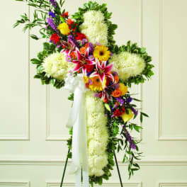 Standing floral cross with white blooms and colorful mixed flowers on an easel