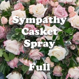 Full casket spray of white and blush pink roses arranged densely with lush foliage.