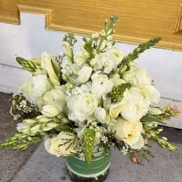 White and pale yellow floral arrangement in a green vase