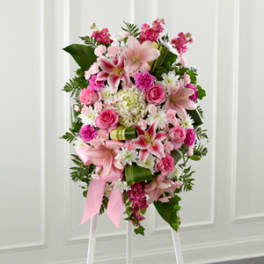 Tall pink and white standing spray with lilies, roses, and carnations on a white easel