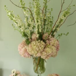 Tall floral arrangement in a glass vase with pale pink and white blooms