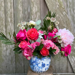 Pink and coral roses arranged in a blue-and-white ceramic vase