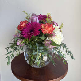 Mixed bouquet of pink, white, and coral flowers in a glass vase