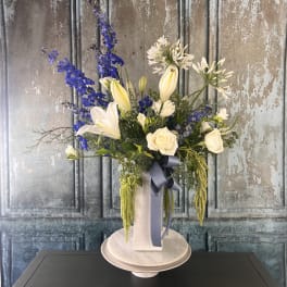 Tall floral arrangement with white lilies, roses, and blue delphinium in a vase