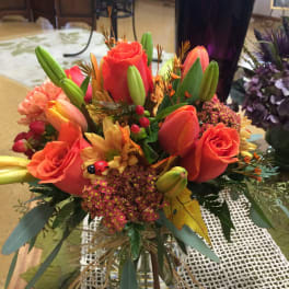 Orange roses and tulips arranged in a glass vase