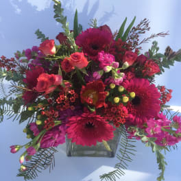 Pink and red mixed bouquet in a clear square vase