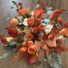 Orange roses and calla lilies with butterflies and a striped ribbon