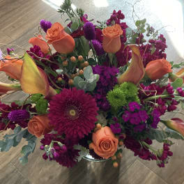 Bright mixed bouquet with orange roses and purple flowers in a vase