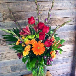 Mixed bouquet with red roses and orange gerbera daisies in a glass vase