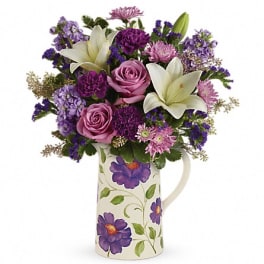 Purple and pink bouquet with white lilies in a floral pitcher vase