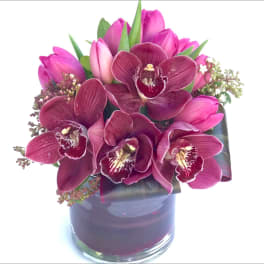Pink orchids and tulips arranged in a glass vase