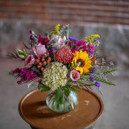 Mixed bouquet in a glass vase with a sunflower and pink blooms