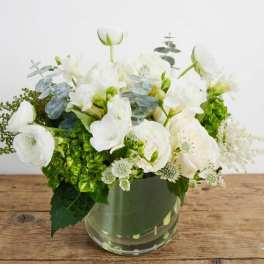 White flowers arranged in a clear glass vase with green accents