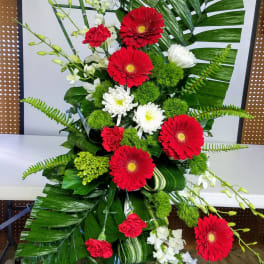 Tall floral spray with red and white flowers and large tropical leaves