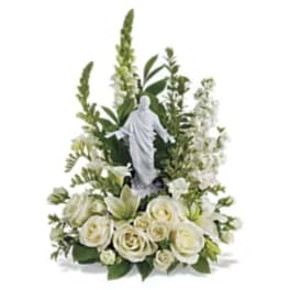 White rose arrangement with a small religious statue centerpiece